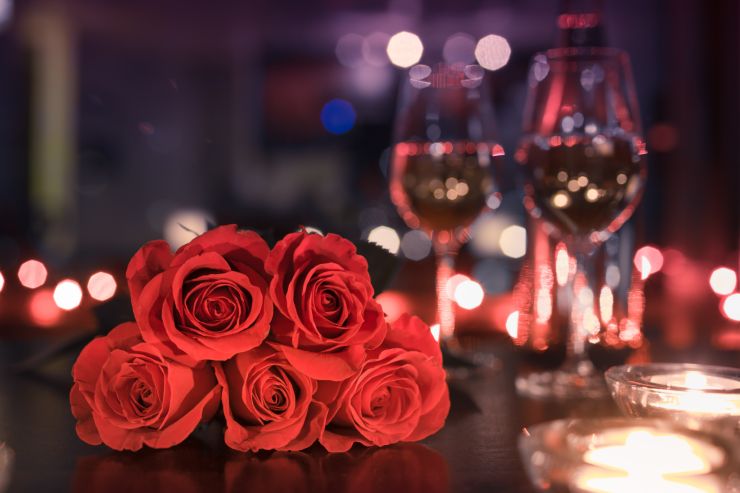 Rose rosse e calici di vino su un tavolo, scena romantica