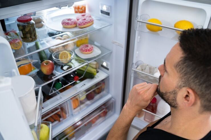 Uomo che guarda dentro il frigorifero pieno di cibo 