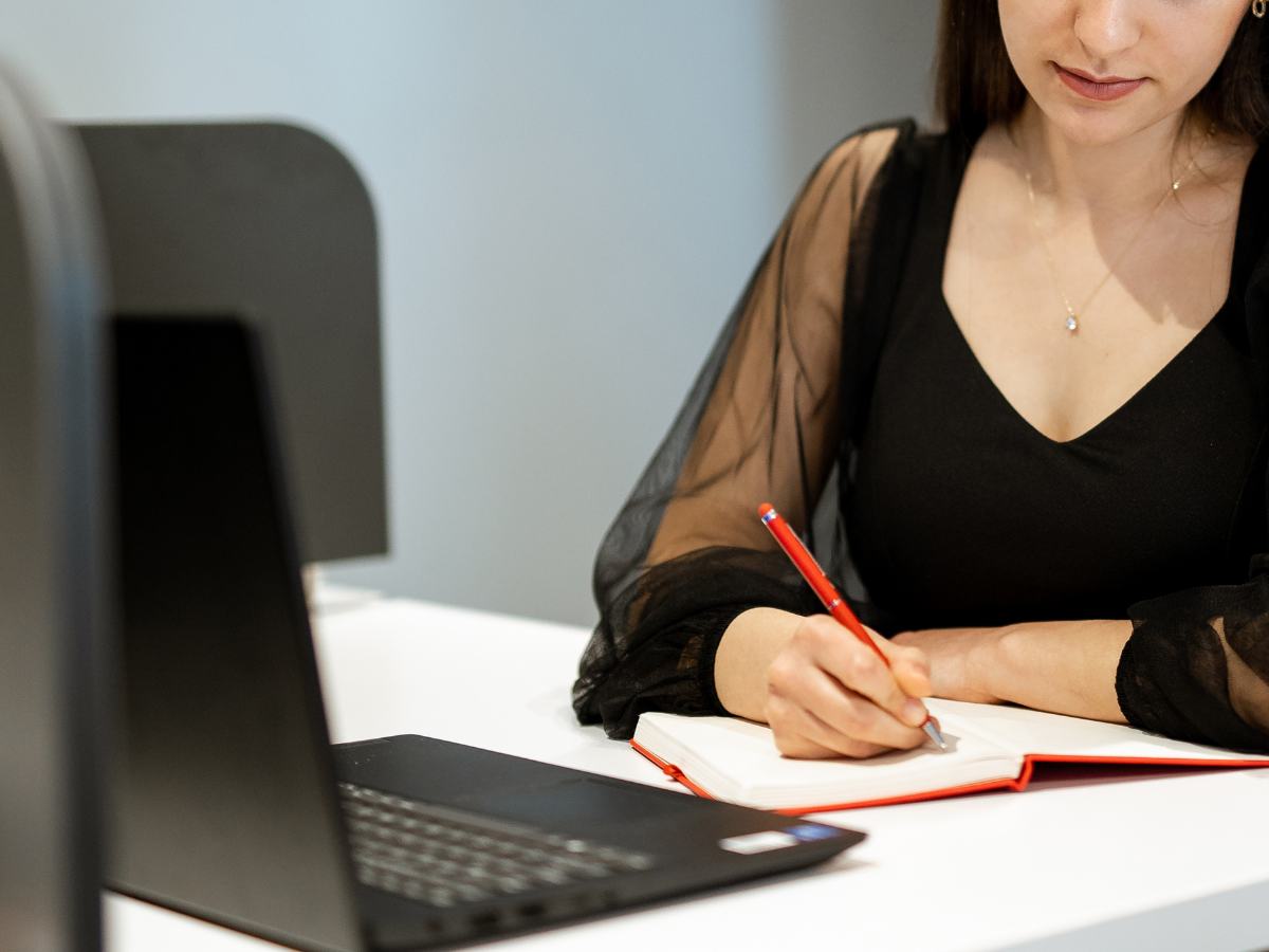 Donna che lavora al pc e scrive su un quaderno