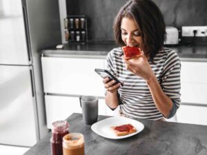 donna con maglia a righe che mangia fette biscottate con marmellata