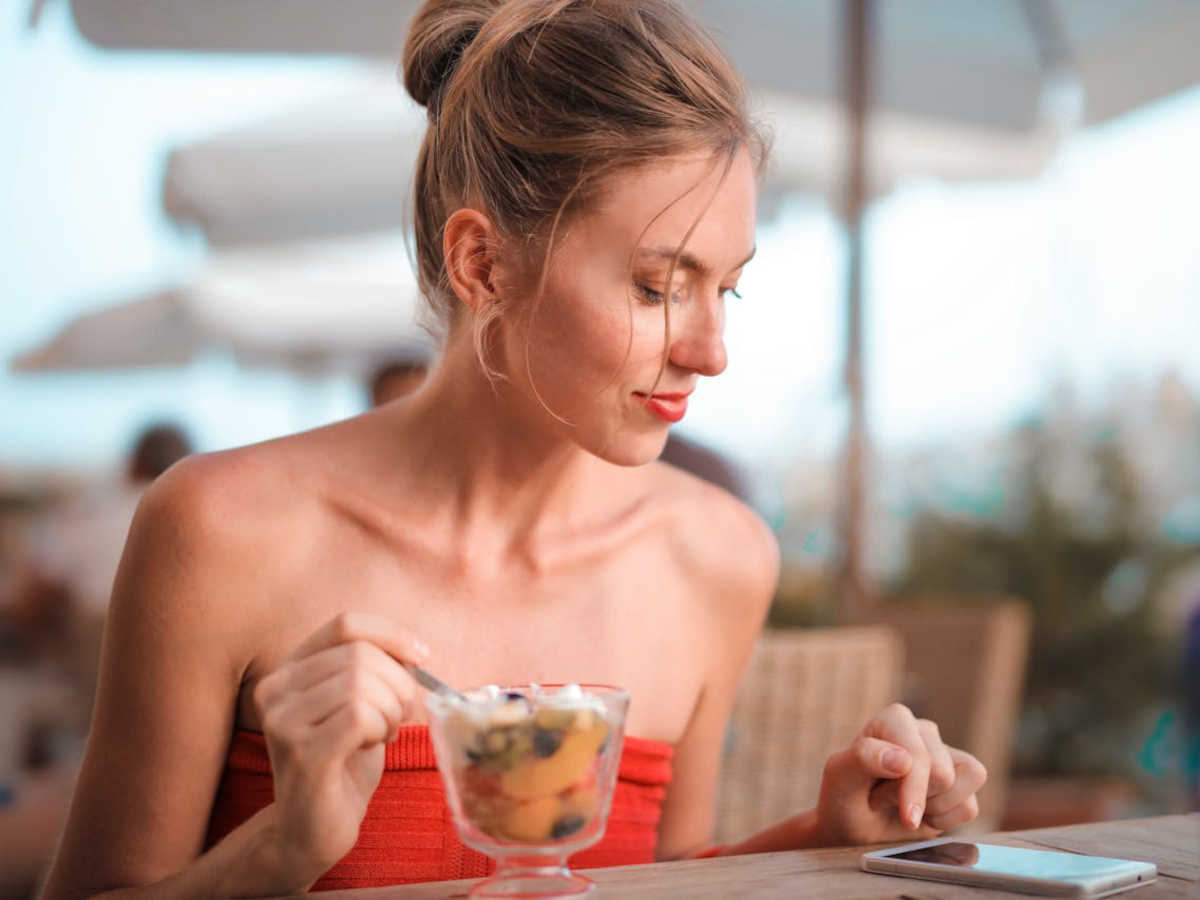 Ragazza che mangia e guarda lo smartphone