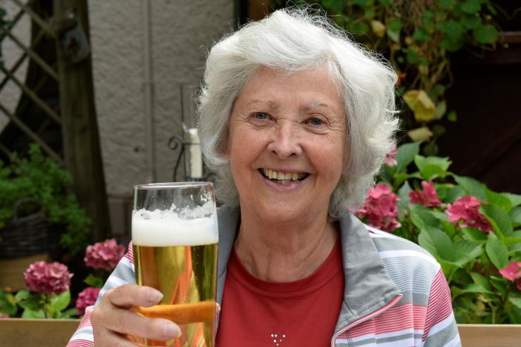 donna anziana che sorride con in mano un bicchiere di birra