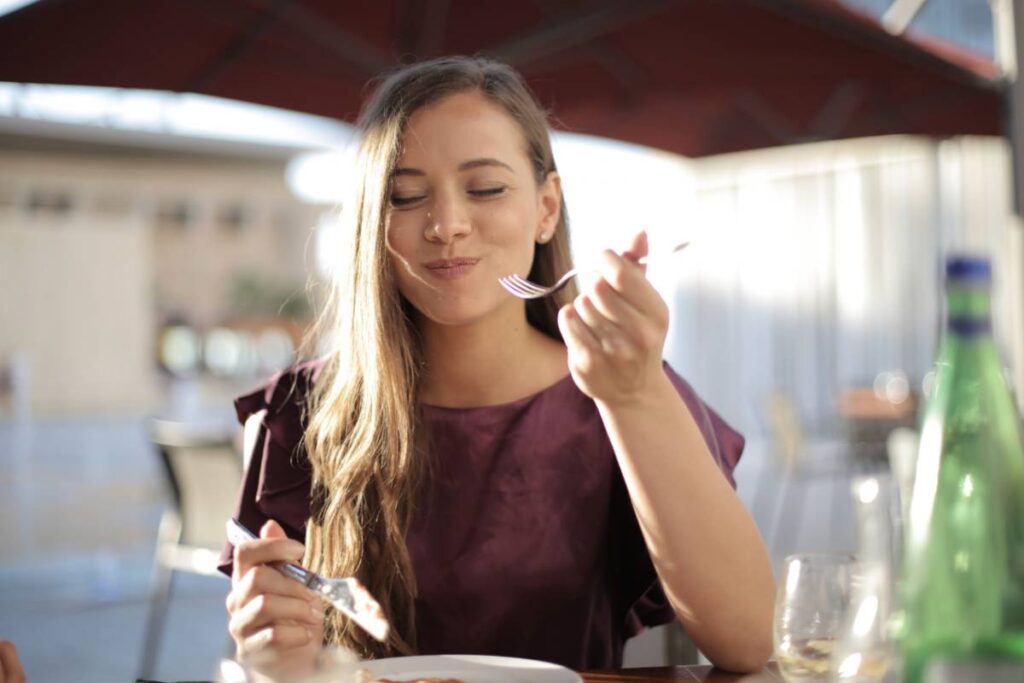 Donna seduta che mangia e sorride