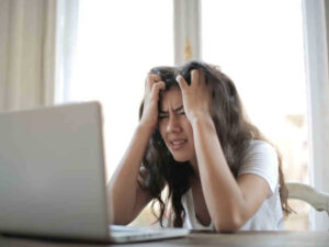 Ragazza con le mani nei capelli davanti al laptop